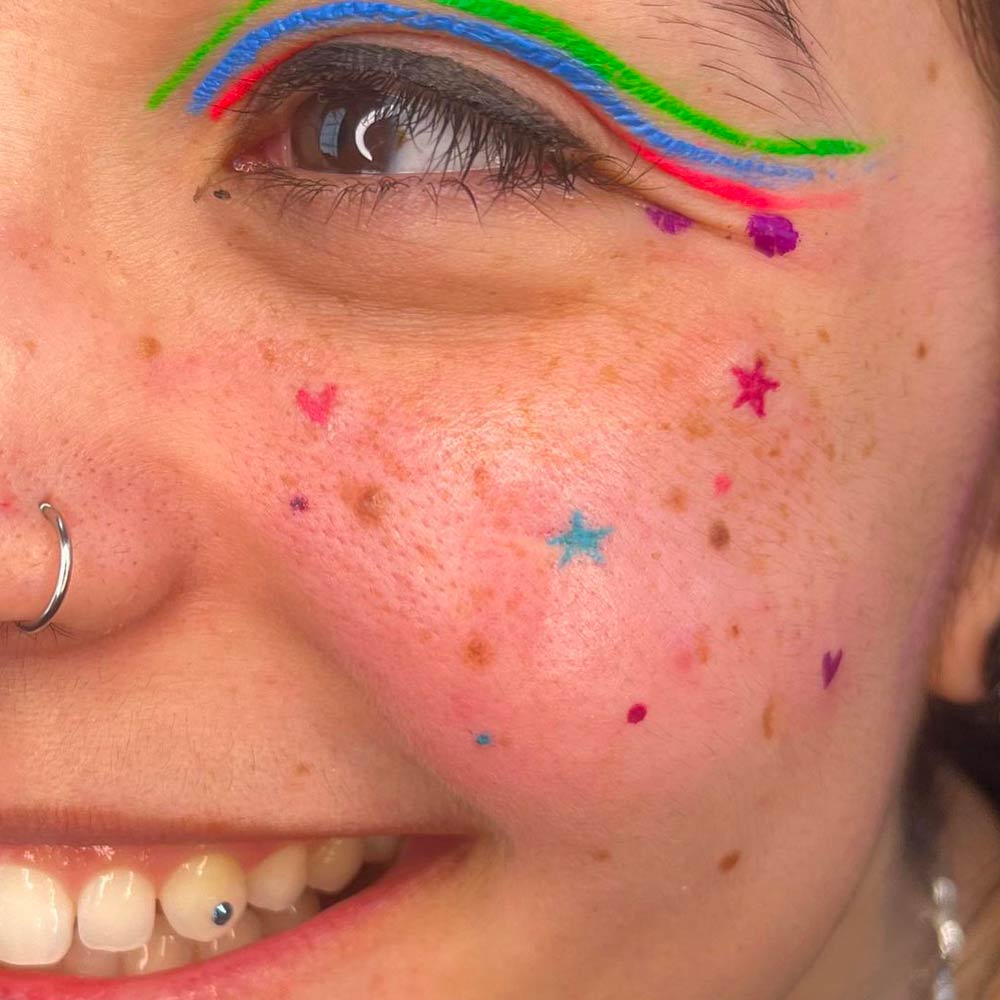 rainbow freckles tattoo on a girl's face